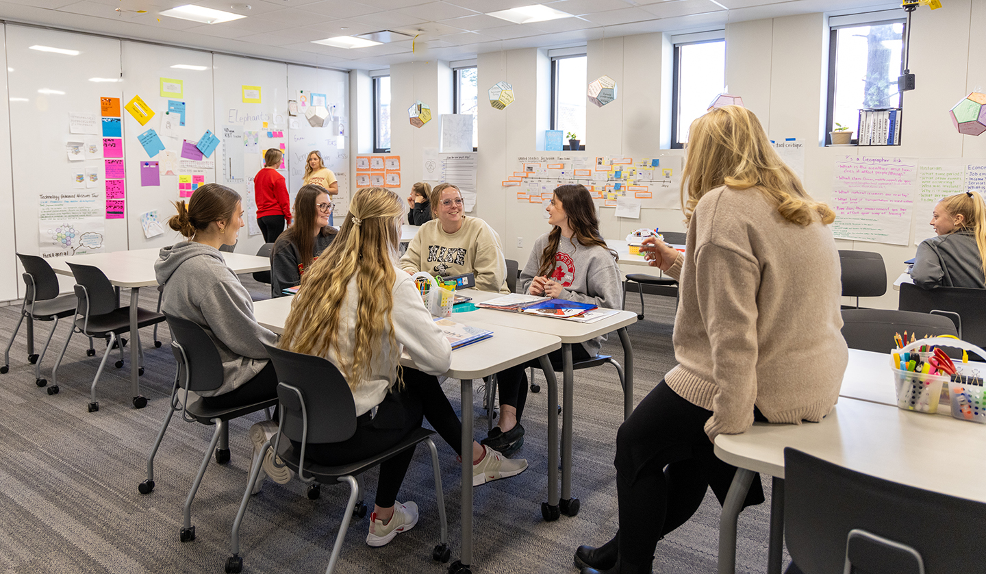 Professor talks with students in classroom