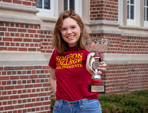 Student with speech and debate trophy