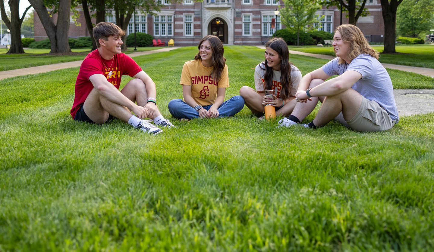 Students sitting in the quad laughing